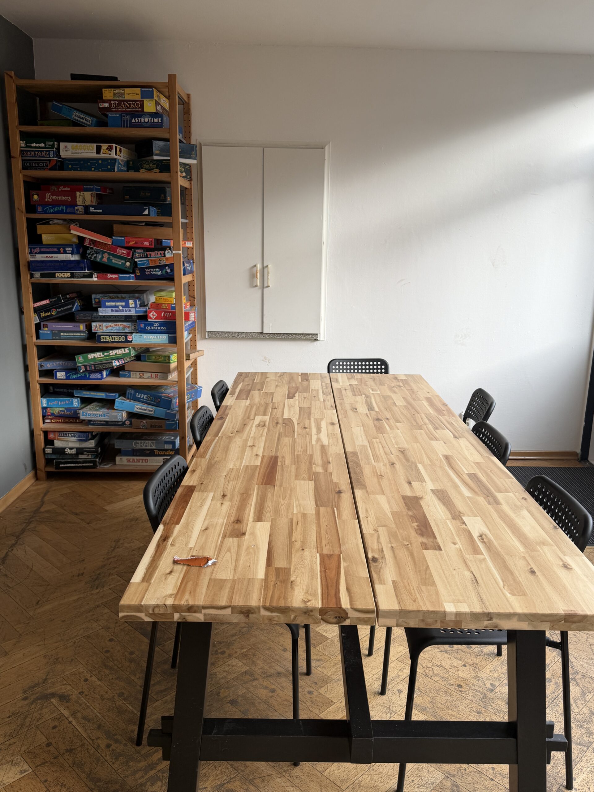 Raum in dem ein großer Holztisch und ein sehr volles Bücherregal.teht