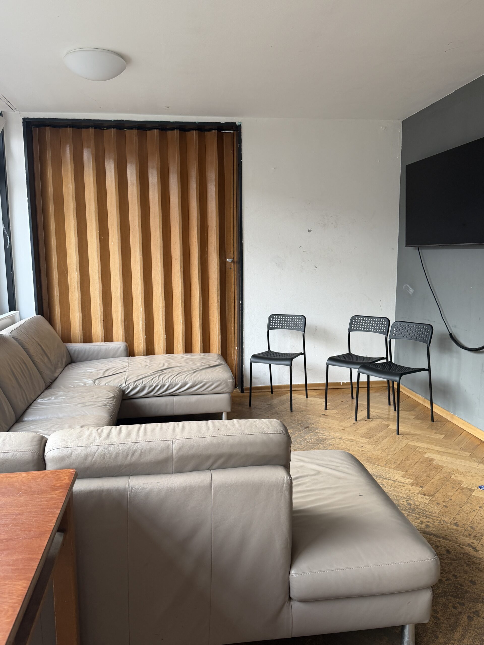 Raum, in dem ein Sofa vor einem an der Wand befestigten Fernseher steht.
